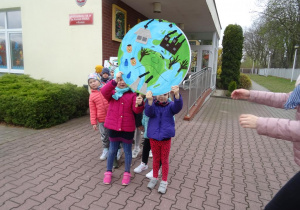 Dwójka dzieci trzyma transparent z planetą Ziemią.
